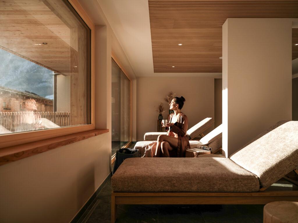 Woman in the relaxation room of the Naturhotel Outside Osttirol - the sun is shining on her face.