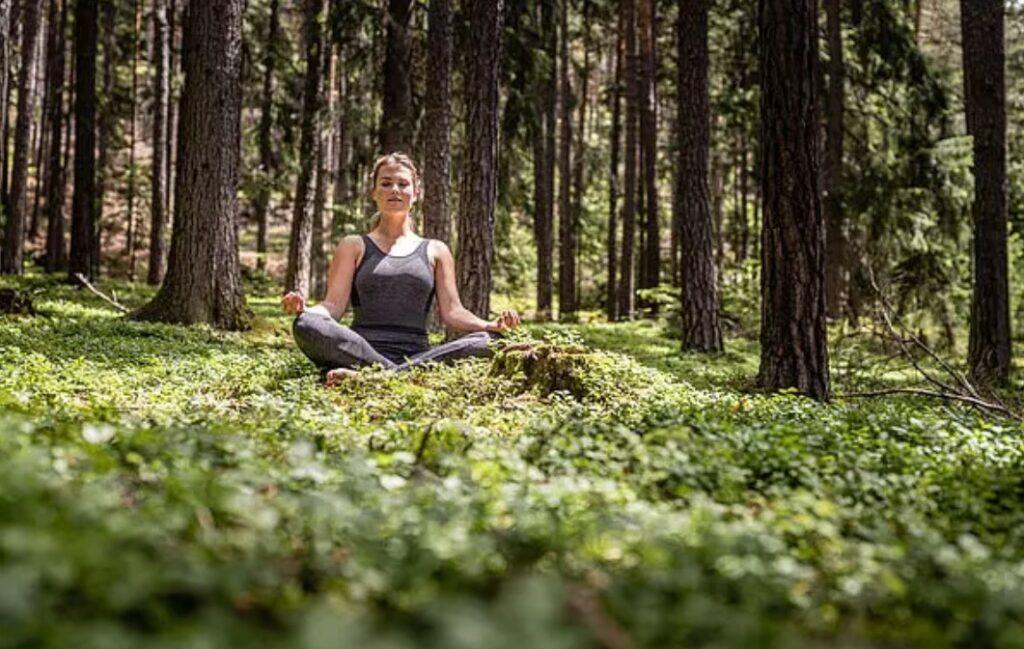 Woman doing forest yoga in the woods in South Tyrol