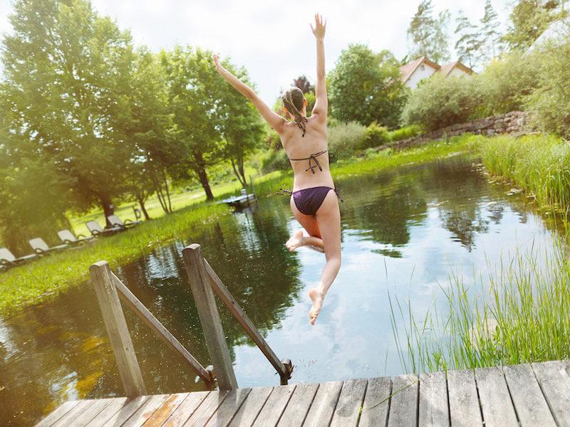 Woman jumping in the natural swimming pond © Biohotel Sturm