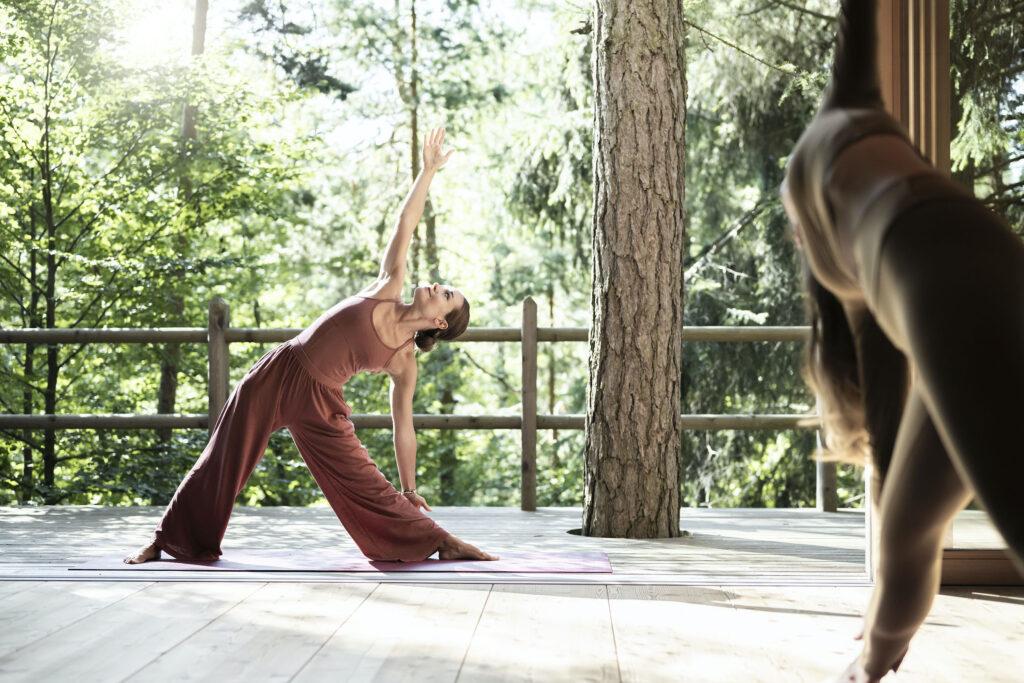 Yoga teacher posing on the terrace in the woods at ADLER Lodge RITTEN in South Tyrol.