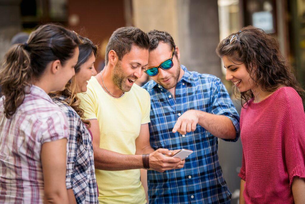 Group of friends in the city looking at their smartphones - Outdoor Escape Game