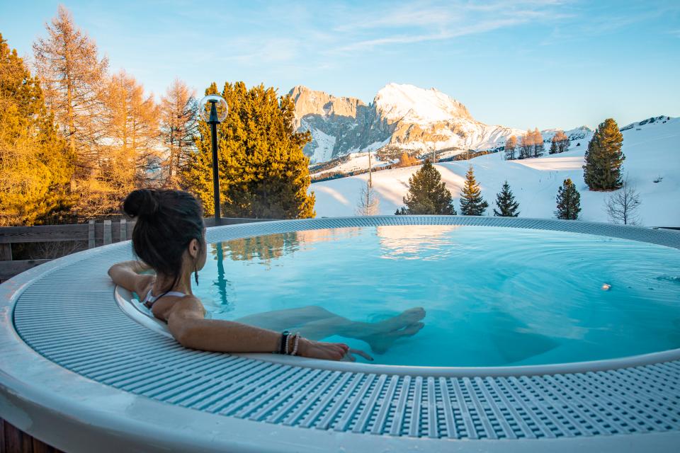 Woman in outdoor whirlpool looking at the Dolomites