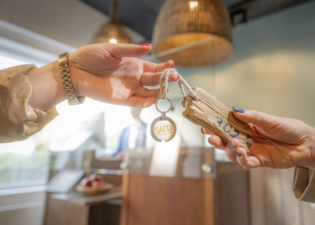 Handing over the keys at the Lifestylehotel SAND. You can see the chip with the driftwood pendant.
