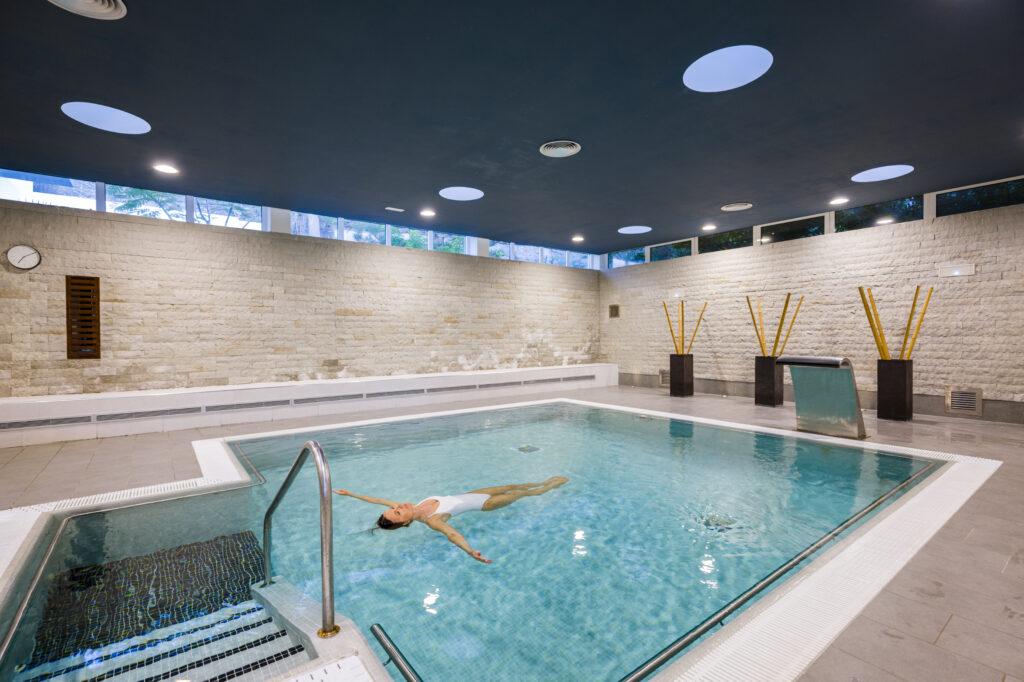 Health hotel with thalassotherapy—woman floating in water. Indoor pool at the Oceano Health Spa Hotel.