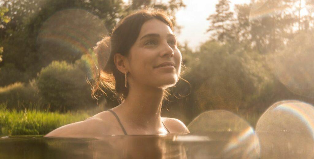 Woman swimming in a natural swimming pond, her face emerging from the water.