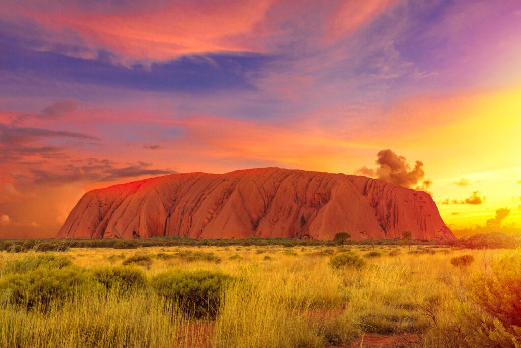 Colorful clouds at sunset in the sky above Ayers Rock in Uluru-Kata Tjuta National Park - in the Living Cultural Landscape, Australia, Northern Territory. The majestic Australian Outback or Red Centre