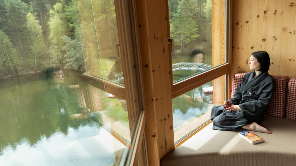 A woman enjoys the view of the lake from her sustainable hotel room in South Tyrol.