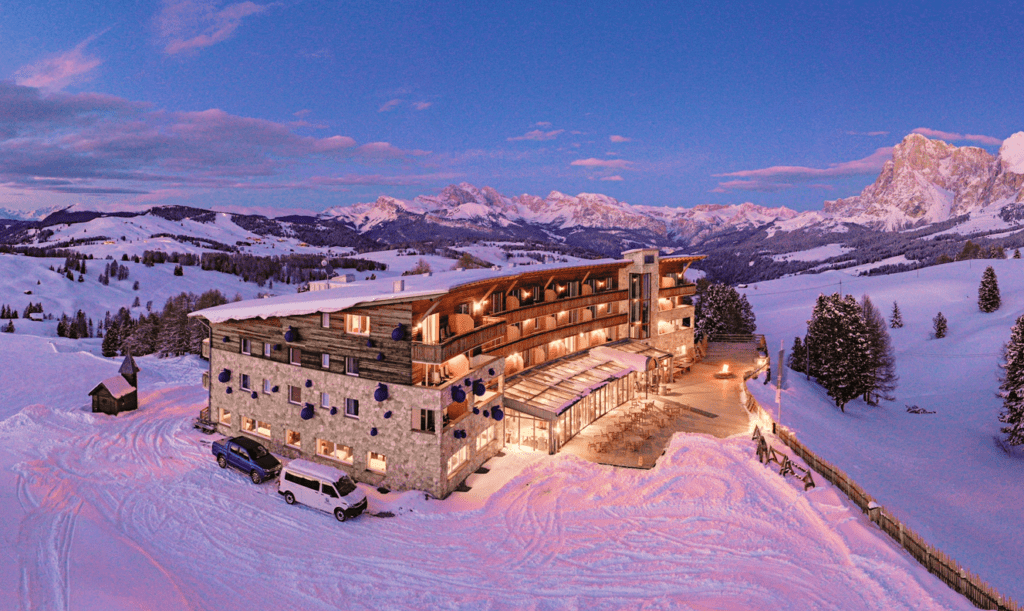 Sustainable ski-in ski-out hotel at dusk Dolomite panorama